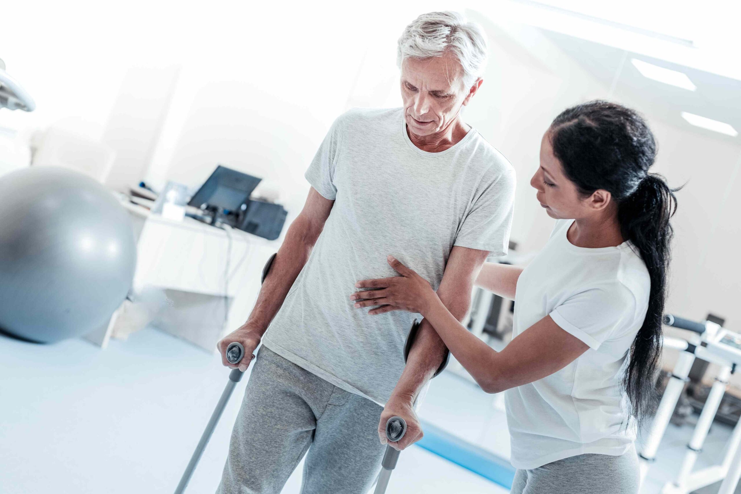 Physiotherapeutin unterstützt einen Patienten beim Aufstehen