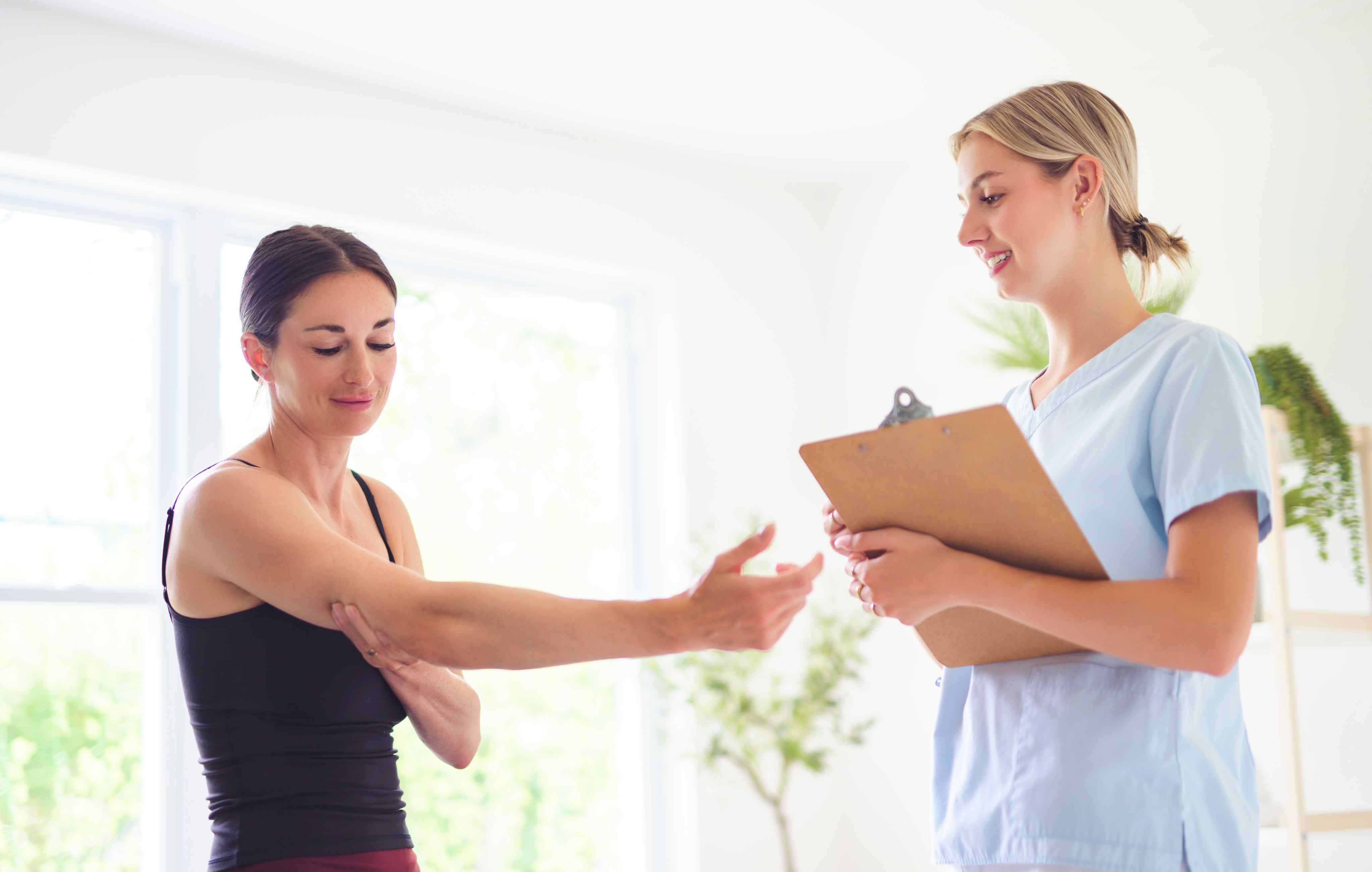 Physiotherapeutin behandelt Patientin am Arm